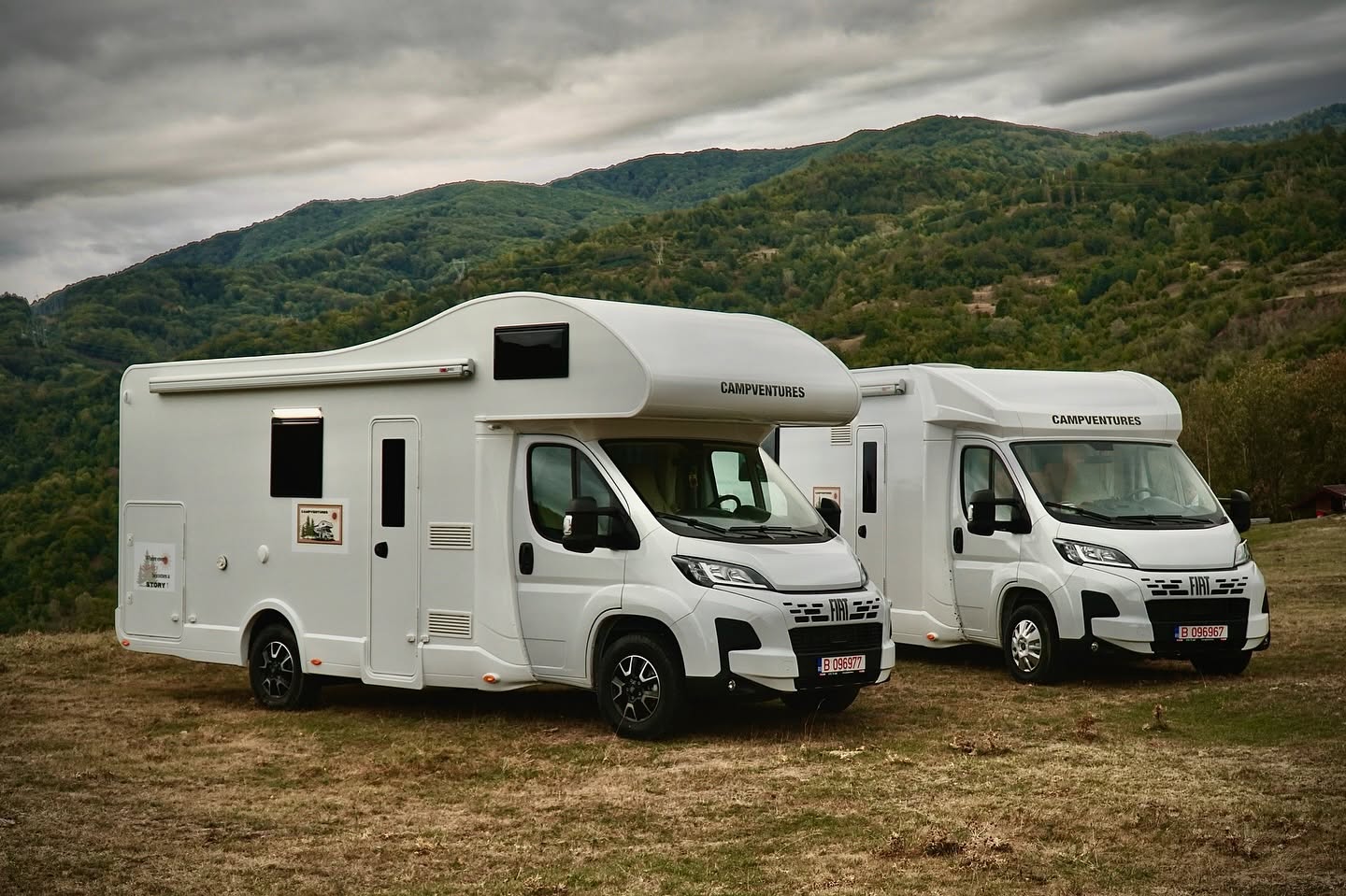 Două rulote CampVentures pe un deal, cu munți în fundal